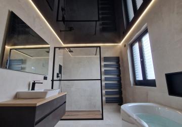 Modernes Bad mit schwarzer Lackspanndecke, umlaufender indirekter LED-Beleuchtung und klaren, geradlinigen Elementen.