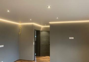 Spanndecke im Flurbereich mit indirekter Lichtvoute entlang der Wände und integrierten Einbauspots.